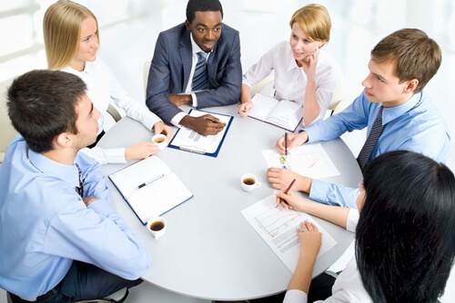 team sitting at a table conducting project management meeting