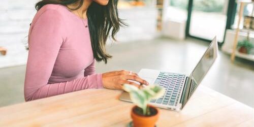 young woman works in public space with laptop