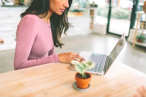 young woman works in public space with laptop