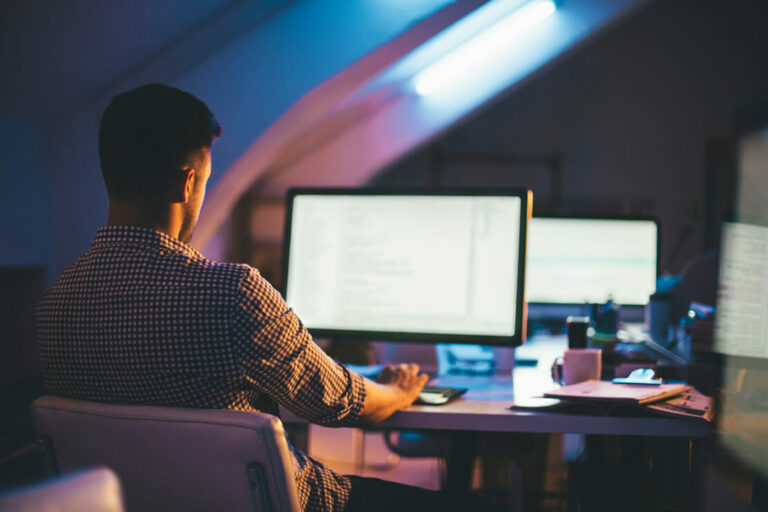 man working alone at his computer in a dark office