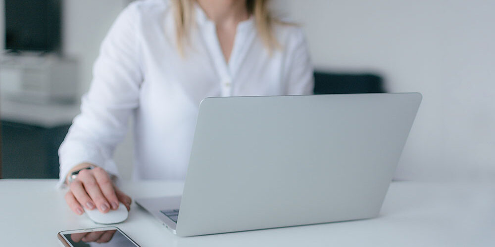 woman at a laptop with her phone on the desk