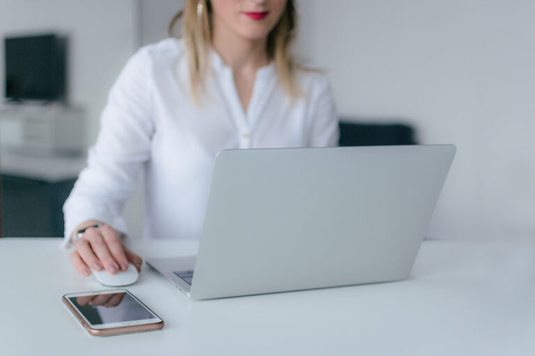 woman at a laptop with her phone on the desk