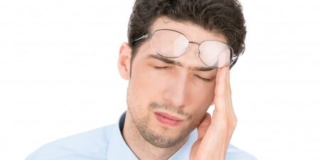 Man rubbing his heads pushing his glasses up onto his forehead