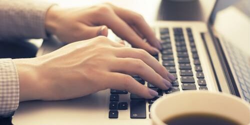 Woman typing on a laptop.