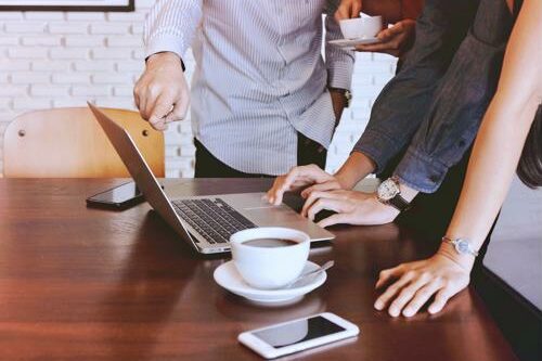 group of employees huddled over computer