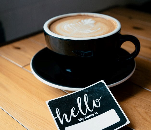 cappuccino in black mug with hello name tag remote onboarding