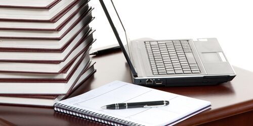 journal sitting at a table with a laptop next to in and a pen on top