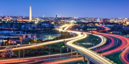 City scape of Washington DC at night with cars driving by