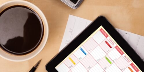 overhead close up of a tablet a computer and a cup of coffee sitting on a desk