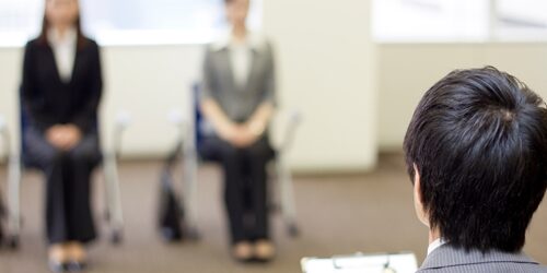 two women sitting to wait for an interview with the boss calling their name