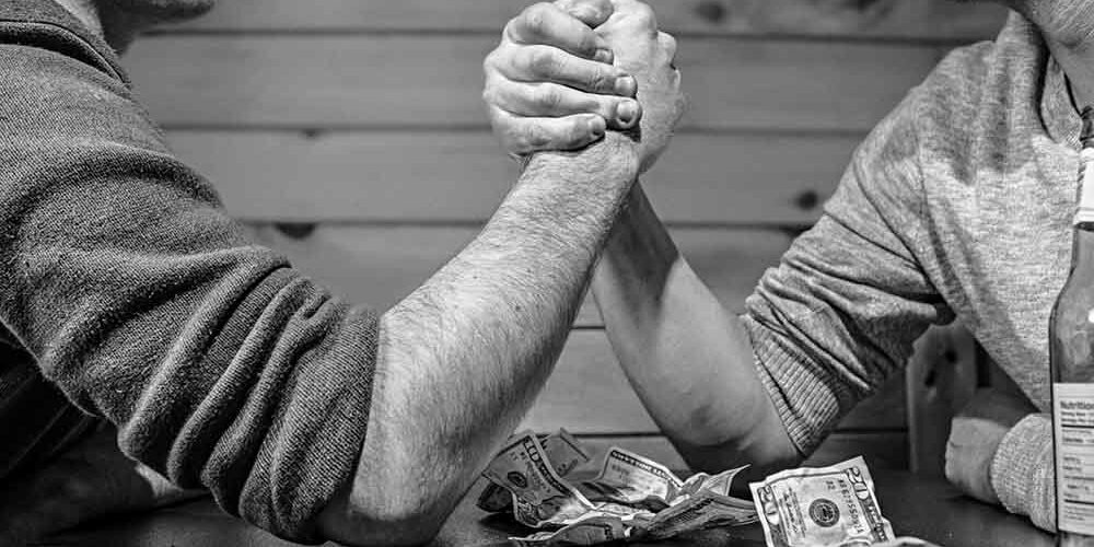 two people arm wrestling for money at a bar