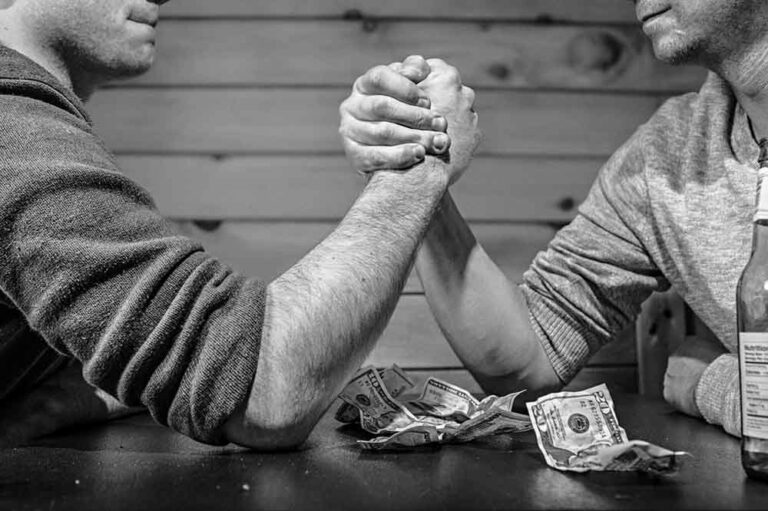two people arm wrestling for money at a bar