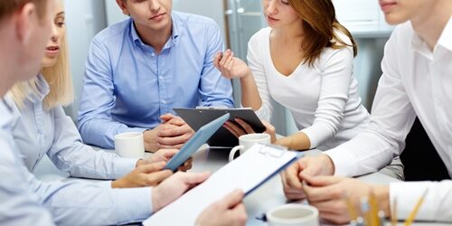 Group of people crowded around a table in a meeting