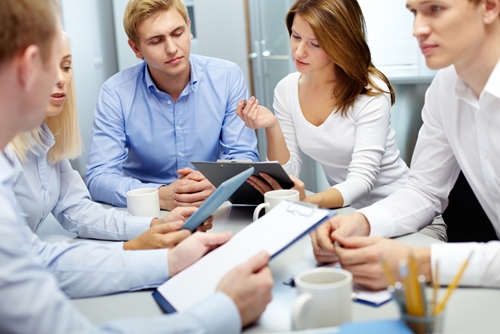 Group of people crowded around a table in a meeting