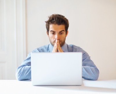 man looking at his computer hopeful