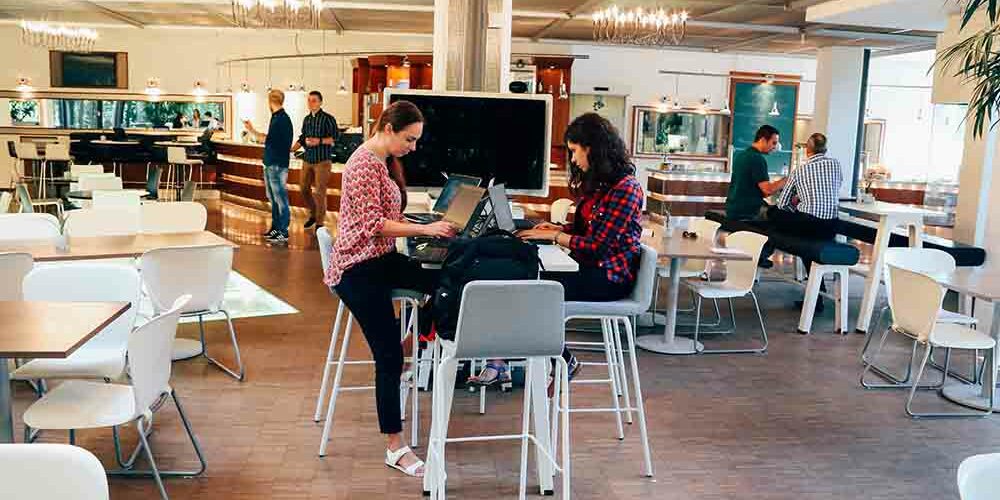 two woman working in a cafe at a communal table