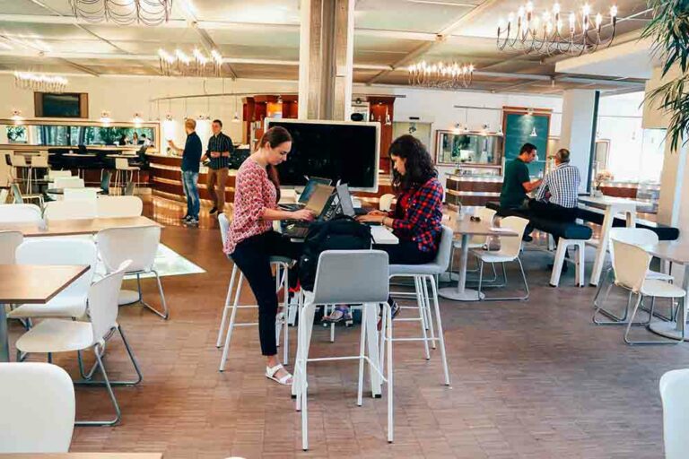 two woman working in a cafe at a communal table