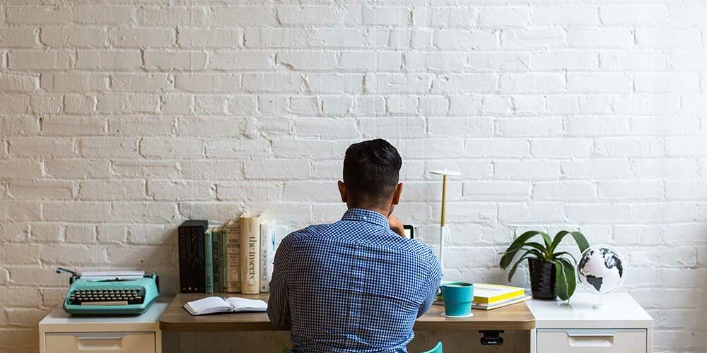 employee-writing-a-resignation-letter-at-a-desk-brick-wall