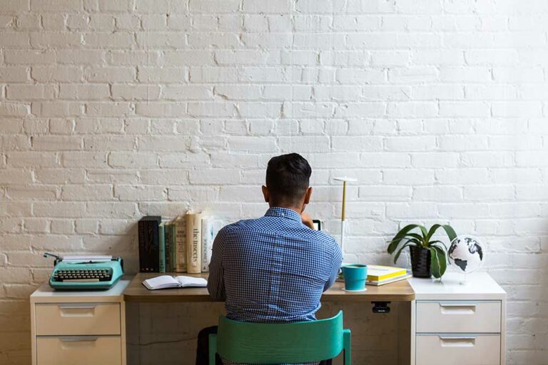 employee-writing-a-resignation-letter-at-a-desk-brick-wall