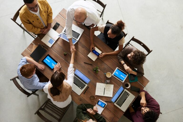 employees around a wooden table hiring solutions