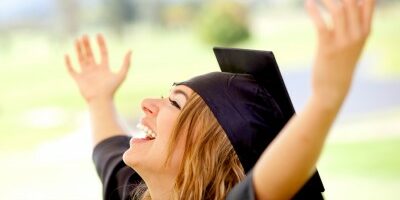 woman celebrating her graduation with her hands in the air