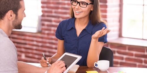 woman talking to a man as he listens and looks at his tablet