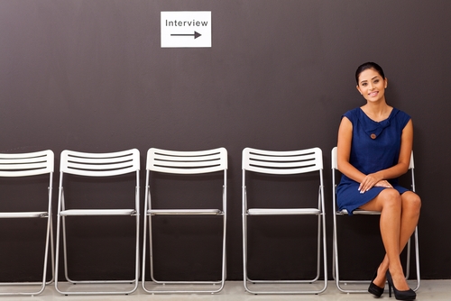 Woman sitting waiting to be interviewed with a row of empty chairs beside her