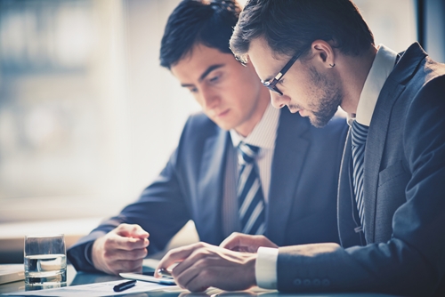 two men looking at a tablet at a table