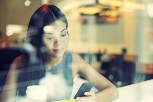 woman looking at her phone in a coffee shop