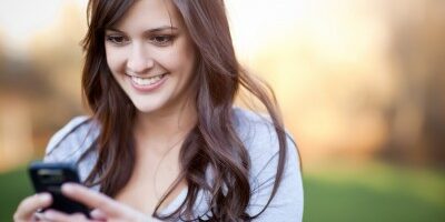 woman smiling at her phone outside