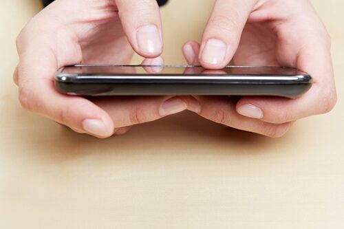 Person holding their phone, close up is on their hands