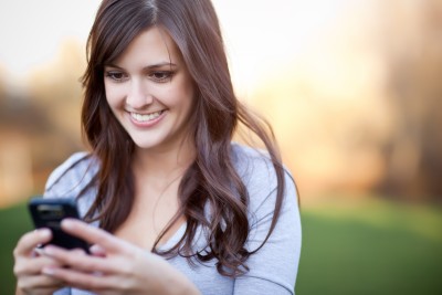 woman smiling at her phone outside