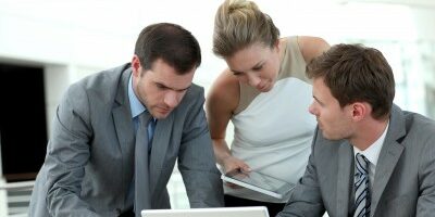 3 coworkers crowd around a computer to look at something