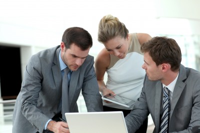 3 coworkers crowd around a computer to look at something