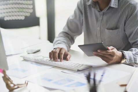 person at computer with tablet second wave of coronavirus