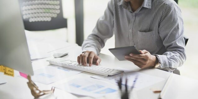 person at computer with tablet second wave of coronavirus