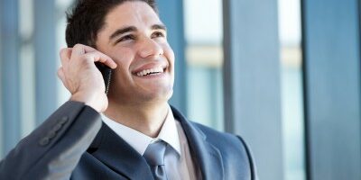 man smiling while he talks on the phone