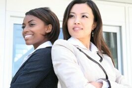 two women back to back with their arms crossed posing