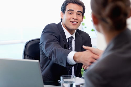 a man shaking a woman's hand at a desk