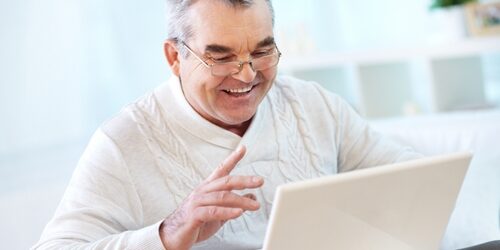 Man smiling as he works on his laptop