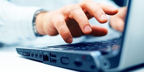 close up of a hand working on a laptop