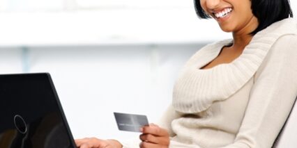Woman on a laptop smiling at her credit card