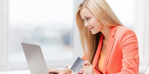 woman on her laptop in an office with a credit card in her hand