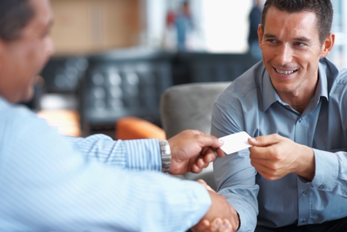 man giving his business card to another man while shaking his head