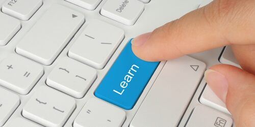 Person pushing a button on a keyboard that says learn