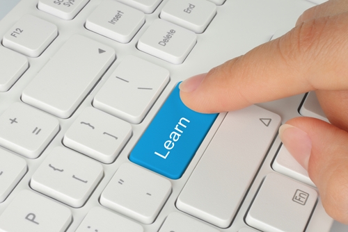 Person pushing a button on a keyboard that says learn