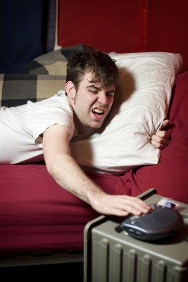 man hitting snooze on his alarm
