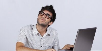 man with a pondering face as he working his laptop looking up