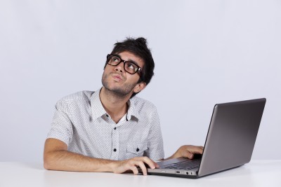 man with a pondering face as he working his laptop looking up