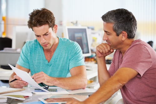 two men looking at paperwork in a bright office